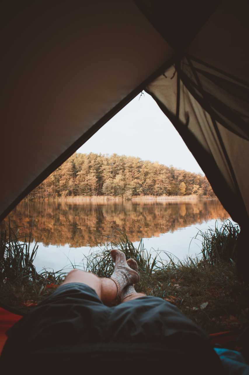 Blick aus einem Zelt auf einen See bei einer Outdoor-Übernachtung